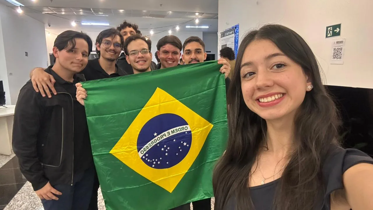 Registro da equipe na Mostratec, reunida com uma bandeira do Brasil.
