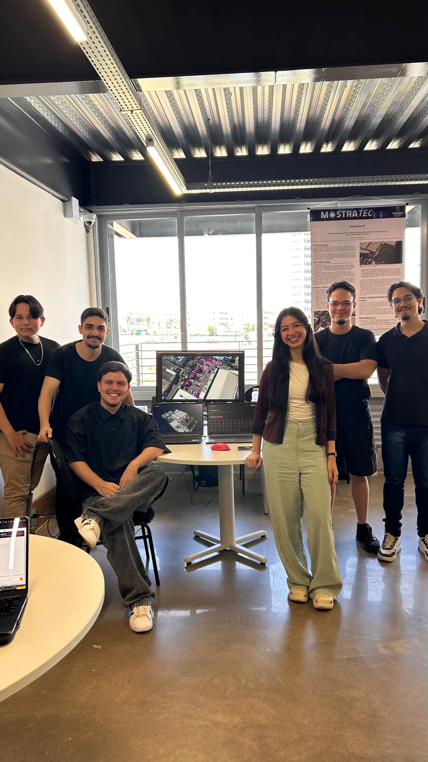 Equipe na Uniube Aberta, ao lado de telas com a detecção das vagas, o modelo 3D e o painel do projeto.